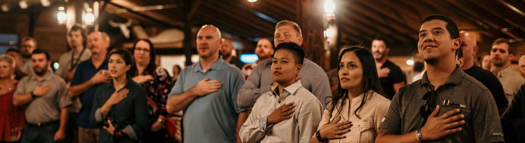 Group of people saying Pledge of Allegiance holding hands over hearts