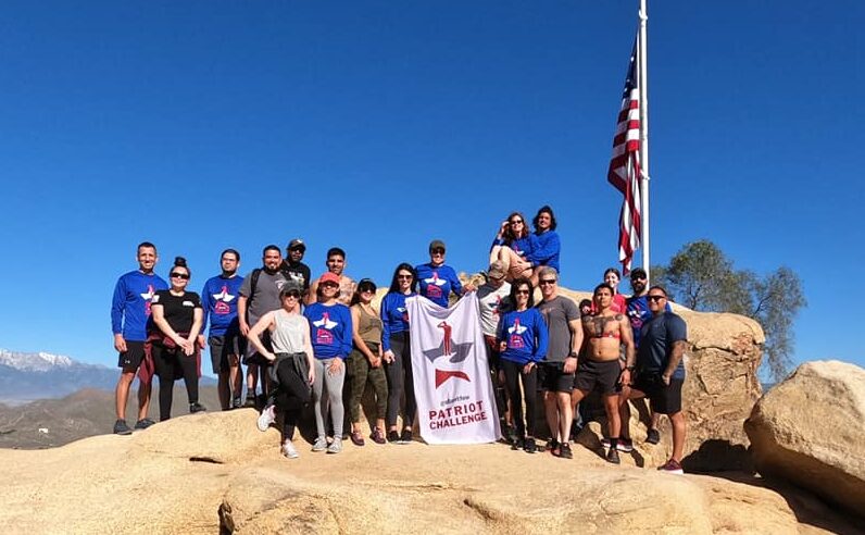 group of people with Patriot Challenge flag on rock
